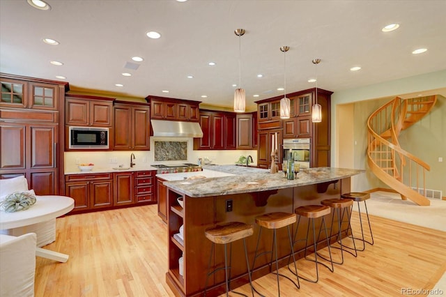 2828 Keystone Dr, Evergreen, CO 80439 - kitchen featuring appliances with stainless steel finishes, under cabinet range hood, light wood-type flooring, recessed lighting, and open shelves