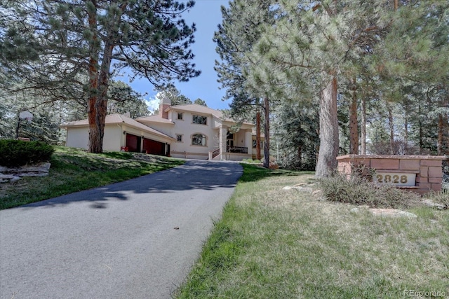 2828 Keystone Dr, Evergreen, CO 80439 - mediterranean / spanish-style house featuring an attached garage, a chimney, stucco siding, and asphalt driveway
