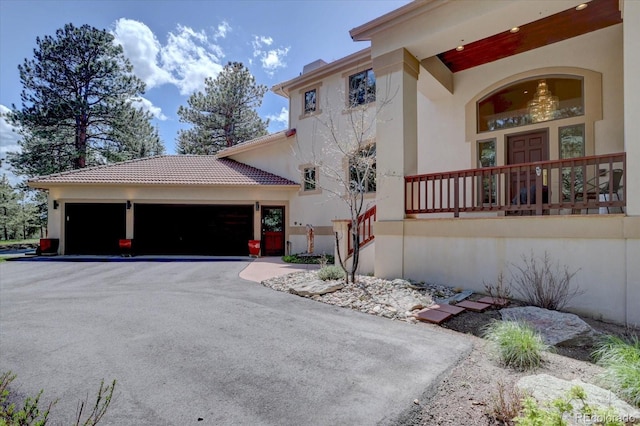 2828 Keystone Dr, Evergreen, CO 80439 - view of side of home featuring stucco siding, an attached garage, asphalt driveway, and a tiled roof