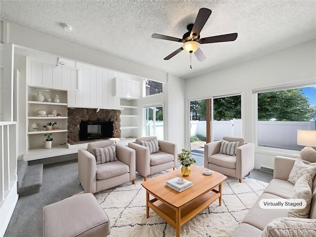 1925 28th Ave Unit 34, Greeley, CO 80634 - living area with a textured ceiling, healthy amount of natural light, a fireplace, a ceiling fan, and light carpet