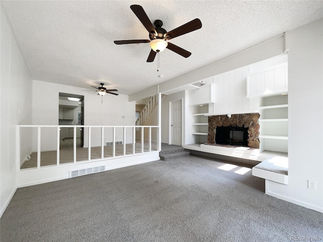 1925 28th Ave Unit 34, Greeley, CO 80634 - unfurnished living room featuring a stone fireplace, carpet flooring, a textured ceiling, a ceiling fan, and stairway