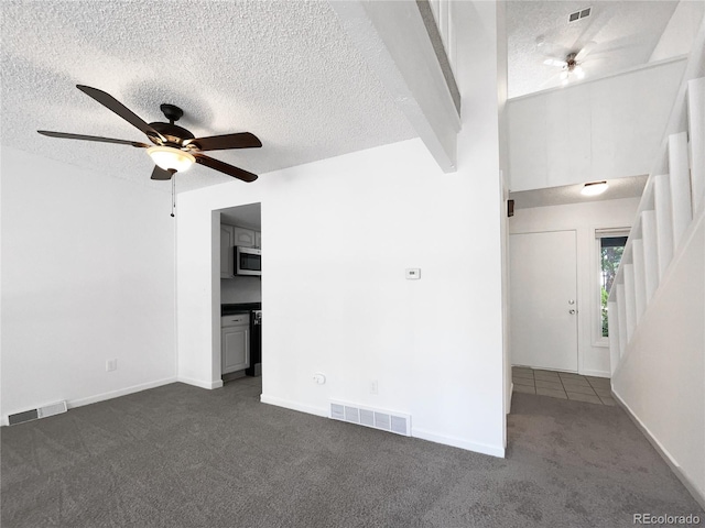 1925 28th Ave Unit 34, Greeley, CO 80634 - unfurnished room with dark carpet, a textured ceiling, a ceiling fan, and stairway