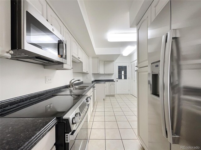 1925 28th Ave Unit 34, Greeley, CO 80634 - kitchen featuring appliances with stainless steel finishes, white cabinetry, light tile patterned flooring, and dark stone counters