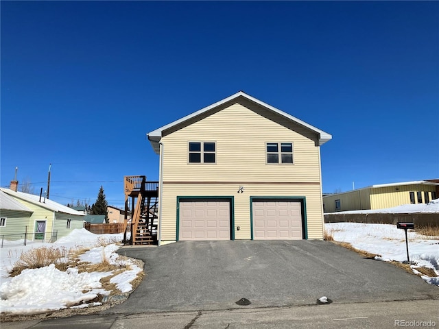 view of front of house with stairway, a garage, driveway, and fence