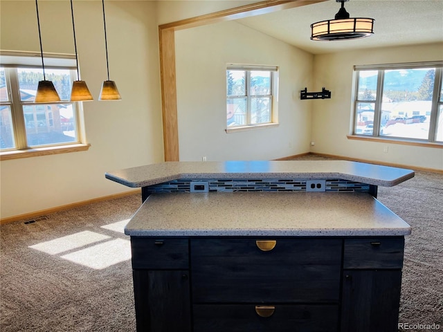 kitchen featuring dark cabinetry, a healthy amount of sunlight, carpet floors, and pendant lighting