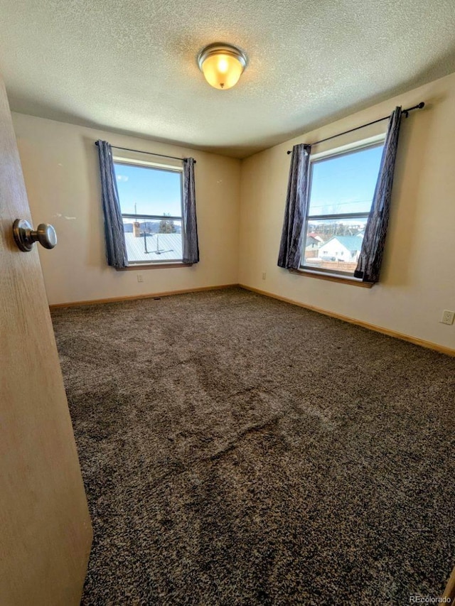 carpeted empty room with baseboards and a textured ceiling