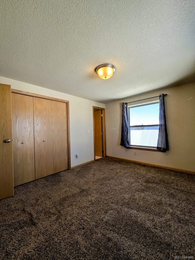 unfurnished bedroom featuring a closet, carpet flooring, a textured ceiling, and baseboards