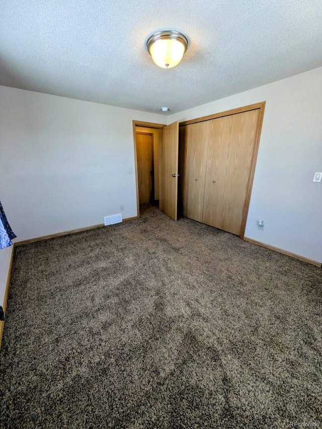 unfurnished bedroom with visible vents, baseboards, a textured ceiling, and carpet flooring