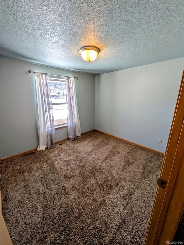 spare room featuring baseboards, carpet floors, and a textured ceiling