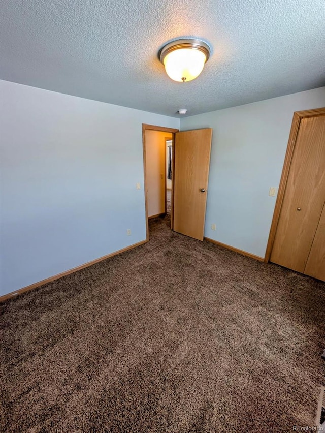 unfurnished bedroom with carpet, baseboards, and a textured ceiling