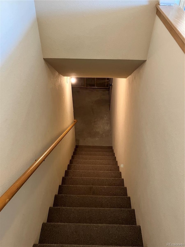 staircase with a textured wall and carpet floors