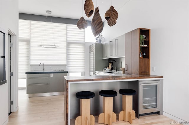 kitchen with gray cabinetry, wine cooler, a wealth of natural light, and kitchen peninsula