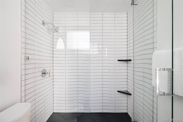 bathroom with a shower with shower door and toilet