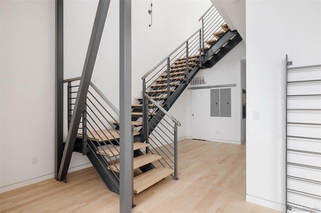 stairway with hardwood / wood-style flooring and a towering ceiling