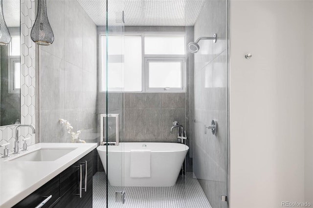 bathroom with vanity, plus walk in shower, tile walls, and tile patterned flooring