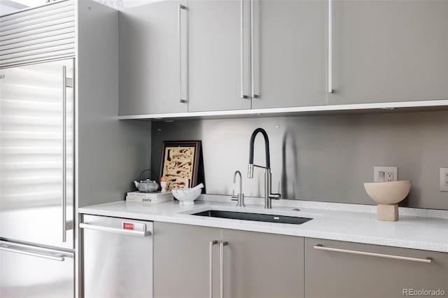 kitchen featuring appliances with stainless steel finishes, gray cabinetry, and a sink