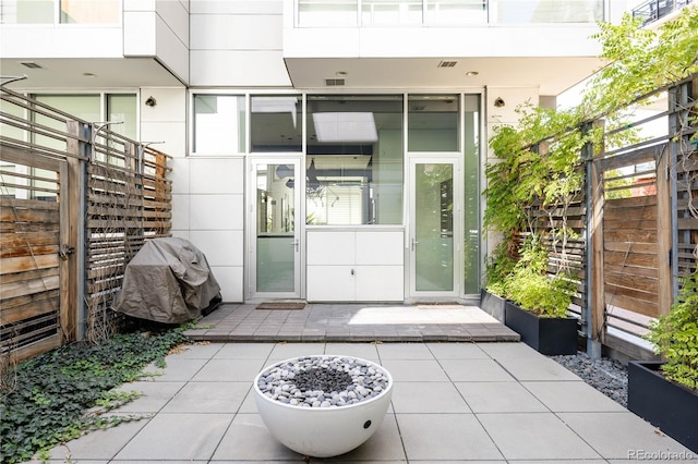 doorway to property featuring stucco siding, visible vents, and a patio area