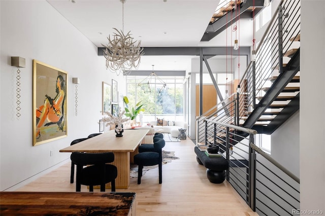 dining space featuring stairs, light wood finished floors, and a chandelier