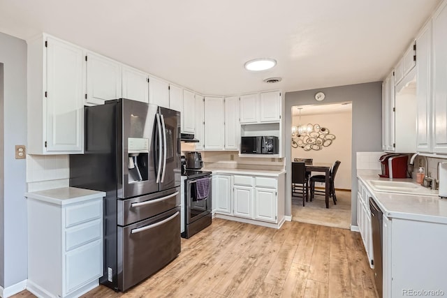 11290 W 77th Dr, Arvada, CO 80005 - kitchen featuring stainless steel appliances, light countertops, white cabinetry, light wood-style floors, and a chandelier