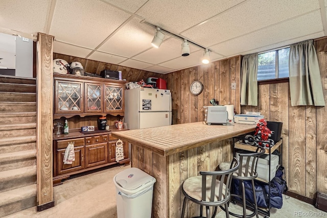 11290 W 77th Dr, Arvada, CO 80005 - kitchen with freestanding refrigerator, wooden walls, light colored carpet, a kitchen bar, and rail lighting