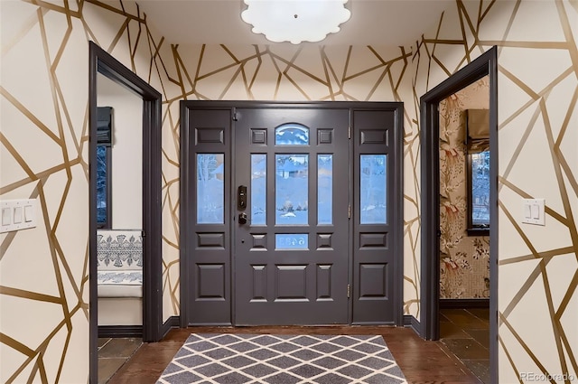 foyer entrance with dark wood-style flooring, baseboards, and wallpapered walls