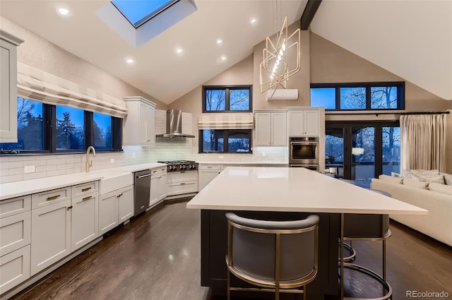 kitchen featuring a kitchen breakfast bar, open floor plan, decorative light fixtures, light countertops, and wall chimney range hood