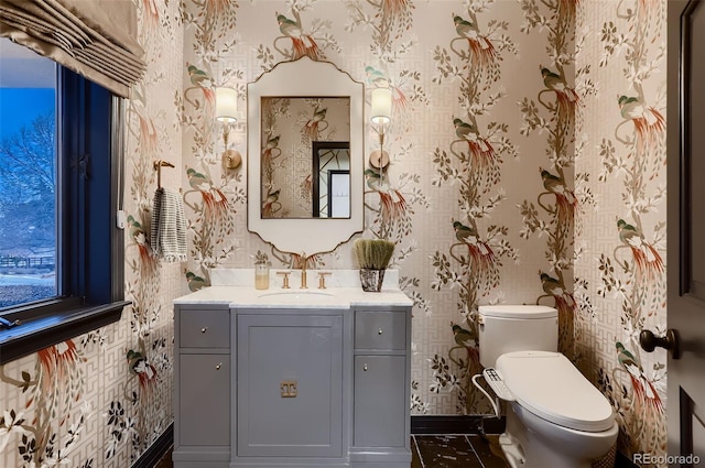 half bath featuring vanity, toilet, and wallpapered walls