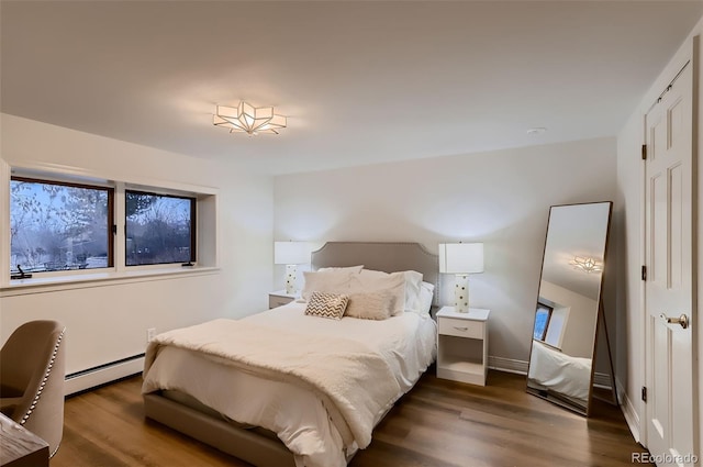 bedroom with a baseboard heating unit, dark wood-type flooring, baseboards, and multiple windows