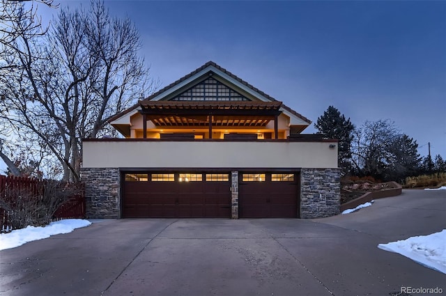 view of front of home featuring a garage, stone siding, driveway, and stucco siding