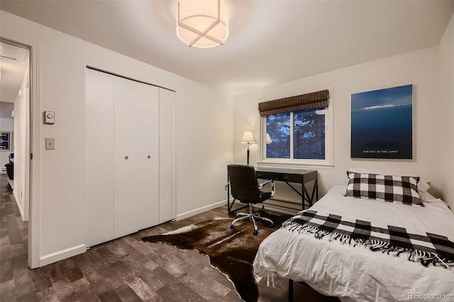 bedroom with dark wood-style floors, baseboards, and a closet