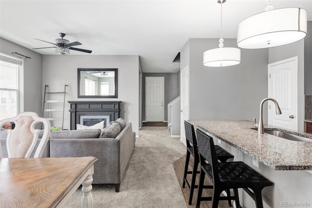 living room with ceiling fan, sink, and light colored carpet