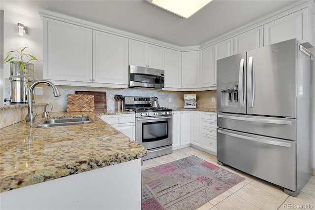 kitchen featuring sink, white cabinetry, backsplash, stainless steel appliances, and light tile patterned flooring