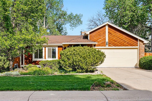 view of front of property with concrete driveway, a front lawn, and a garage