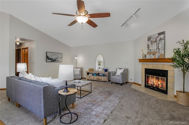 carpeted living area with lofted ceiling, a tiled fireplace, a ceiling fan, track lighting, and baseboards