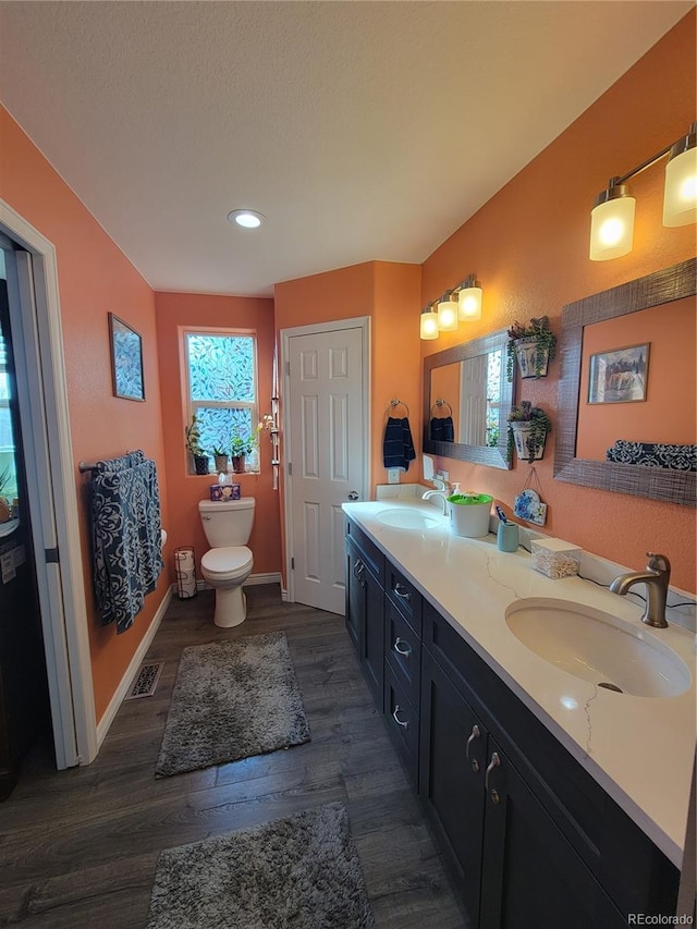 bathroom with hardwood / wood-style flooring, vanity, toilet, and a wealth of natural light