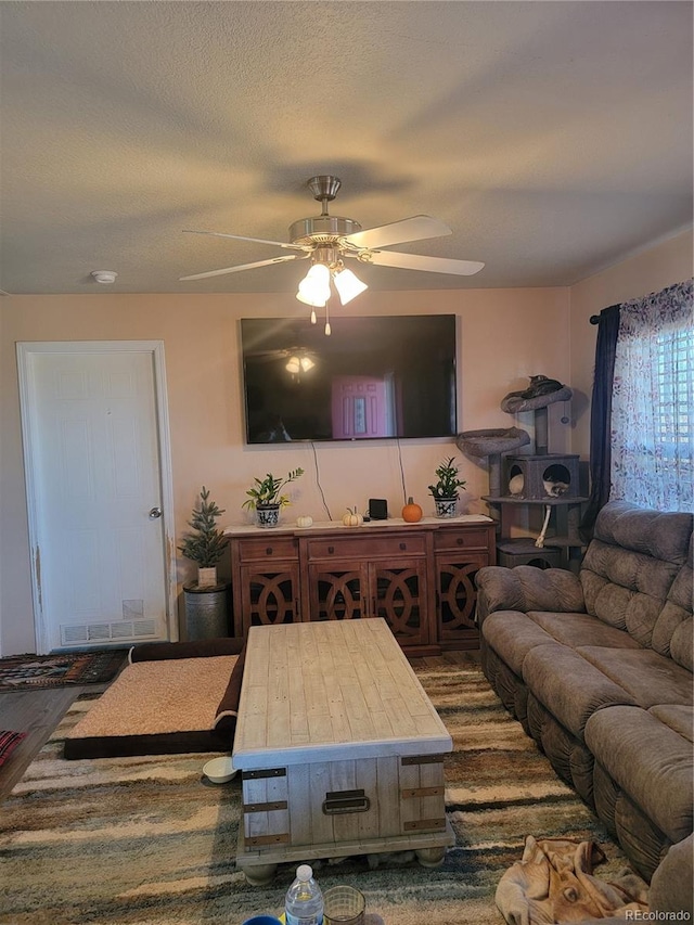 living room with ceiling fan and a textured ceiling