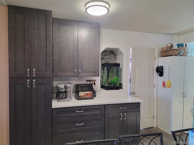 kitchen featuring hardwood / wood-style floors, dark brown cabinets, and a textured ceiling