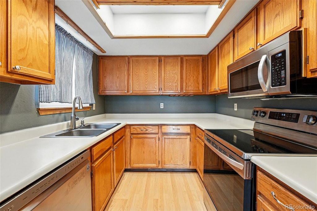 19192 E Wyoming Pl Unit 108, Aurora, CO 80017 - kitchen with light wood-style flooring, appliances with stainless steel finishes, a sink, light countertops, and brown cabinets