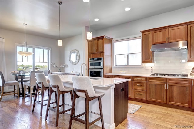 365 Casalon Pl, Superior, CO 80027 - kitchen featuring under cabinet range hood, stainless steel appliances, light countertops, brown cabinets, and recessed lighting