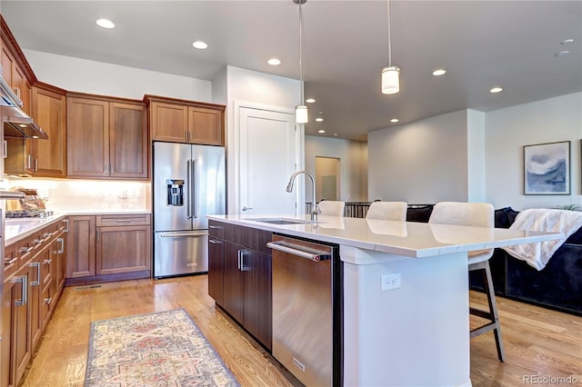 365 Casalon Pl, Superior, CO 80027 - kitchen featuring appliances with stainless steel finishes, a sink, a breakfast bar area, light wood-type flooring, and an island with sink