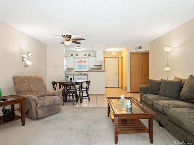 living room with ceiling fan, sink, light tile patterned floors, and a textured ceiling