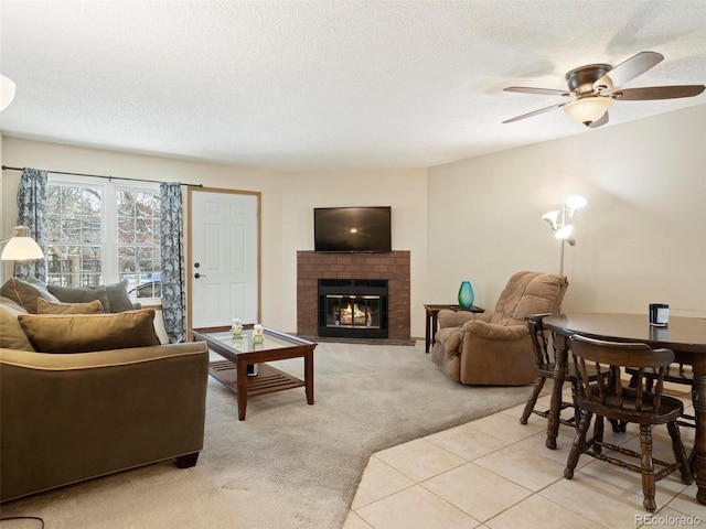 living room with a textured ceiling, a fireplace, ceiling fan, and light carpet