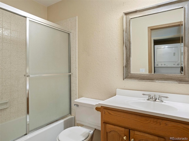 full bathroom featuring bath / shower combo with glass door, vanity, stacked washing maching and dryer, and toilet