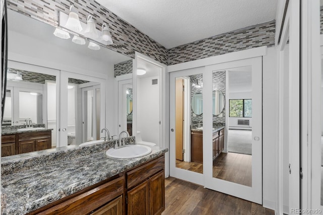 bathroom featuring wood-type flooring, vanity, french doors, and a textured ceiling