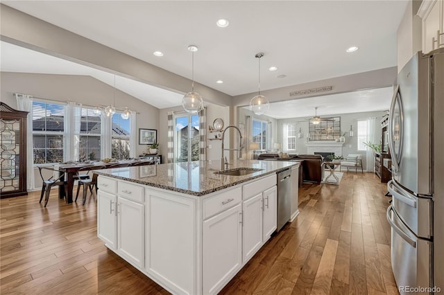 kitchen featuring white cabinetry, sink, stainless steel appliances, and a center island with sink