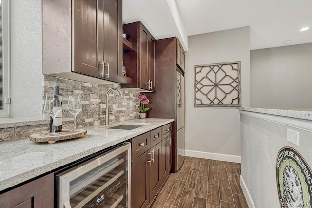 bar featuring sink, dark hardwood / wood-style floors, wine cooler, light stone counters, and tasteful backsplash