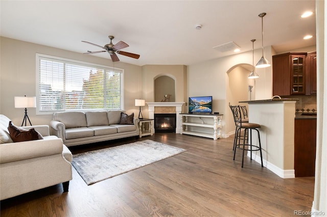 living room featuring ceiling fan and dark wood-type flooring