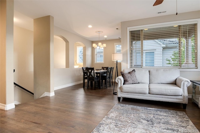 living room featuring ceiling fan with notable chandelier and dark hardwood / wood-style floors