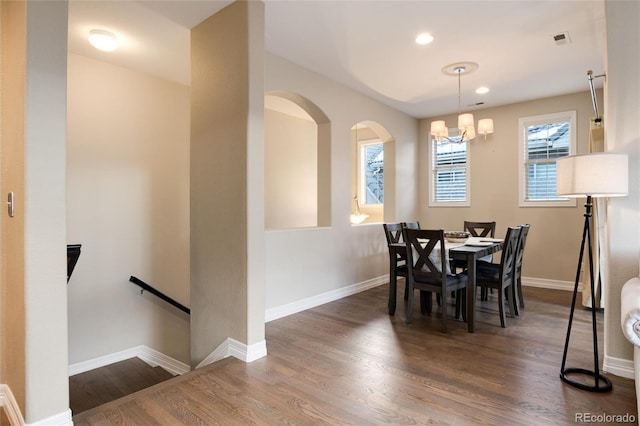 dining room with dark hardwood / wood-style floors and an inviting chandelier