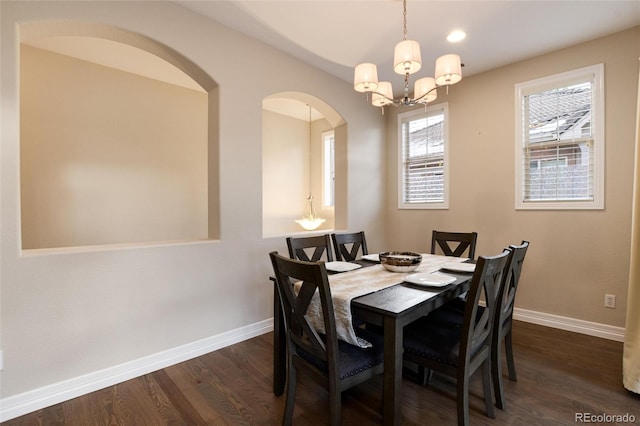 dining area with dark hardwood / wood-style flooring and an inviting chandelier